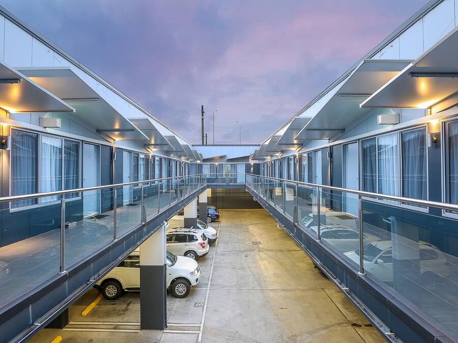 Un edifici modern amb zona de pàrquing coberta i un passadís de vidre.