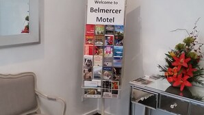 Un área de recepción con un cartel que dice 'Información para Visitantes' y un letrero que dice 'Bienvenido al Motel Belmercer'.