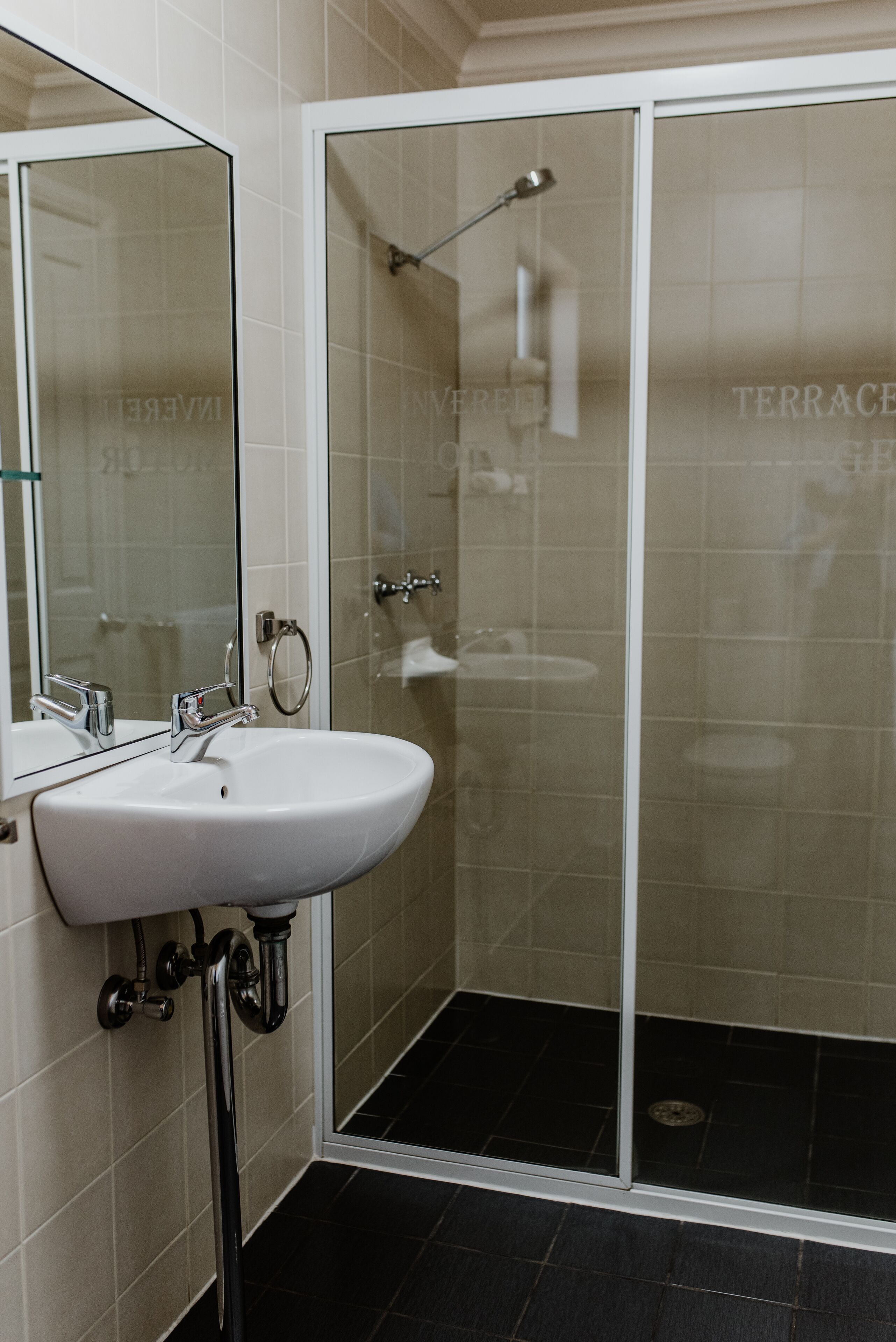 A bathroom with a white sink, a glass shower enclosure, and tiled walls.