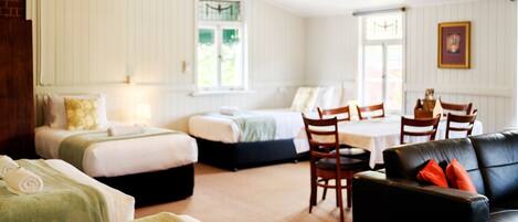 Une chambre d’hôtel avec deux lits, une table à manger et un canapé en cuir noir.