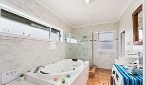 A modern bathroom with a freestanding bathtub, a glass-enclosed shower, a vanity with a sink, and a window. - Southview Boutique Guest House (Bulli)