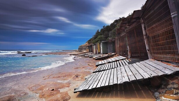 Una platja amb passeres de fusta que condueixen a cabanes de platja.