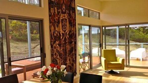A modern interior with a dining area, large windows, and a view of the outdoors. - a Dune Escape (Emu Bay)