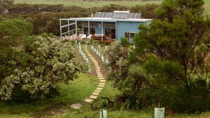 A blue building with solar panels, surrounded by trees and a pathway leading to it. - a Dune Escape (Emu Bay)