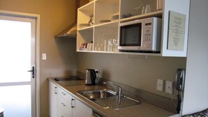 A compact kitchen with a microwave, sink, and cabinets.