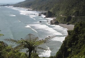Eine Küstenlandschaft mit Strand, Wellen und üppigem Grün.