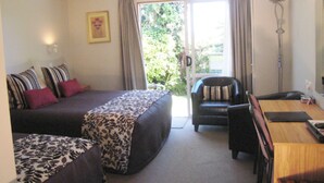 A bedroom with a bed, a chair, a desk, and a window with curtains.