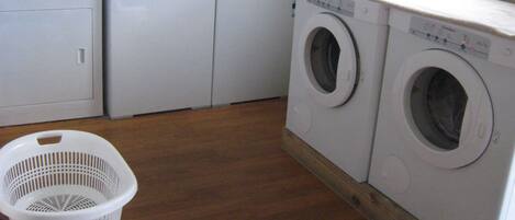Un cuarto de lavandería con dos lavadoras, un secador y una cesta de ropa.