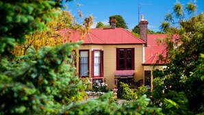 Un edificio de dos pisos con techo rojo, una chimenea y una zona de recepción.