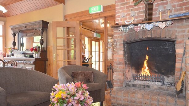Una habitación acogedora con chimenea, un sofá, una mesa con un florero y una señal de salida.