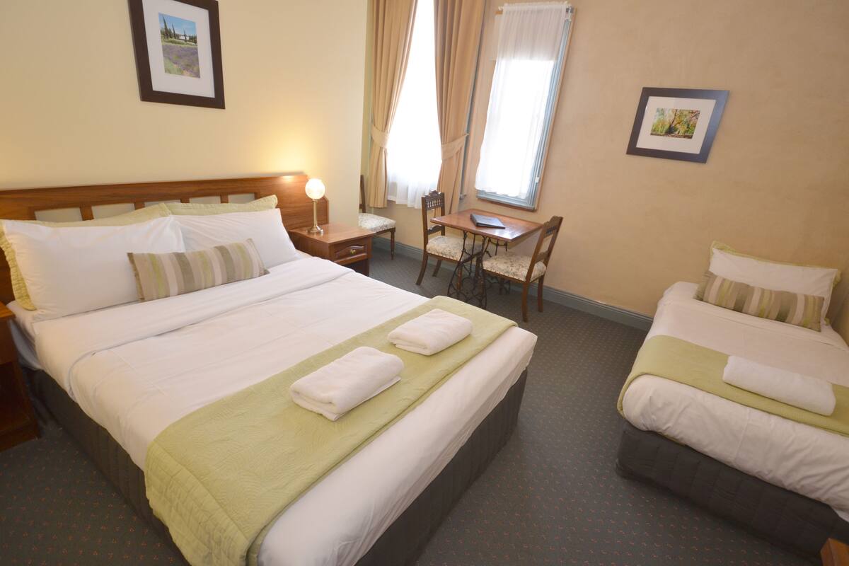 A hotel room with two beds, a desk, and a chair.