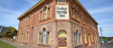 A brick building with a sign reading "Central Springs Inn Motel" and "Spa Suites Open Fire Suites Conference Room."