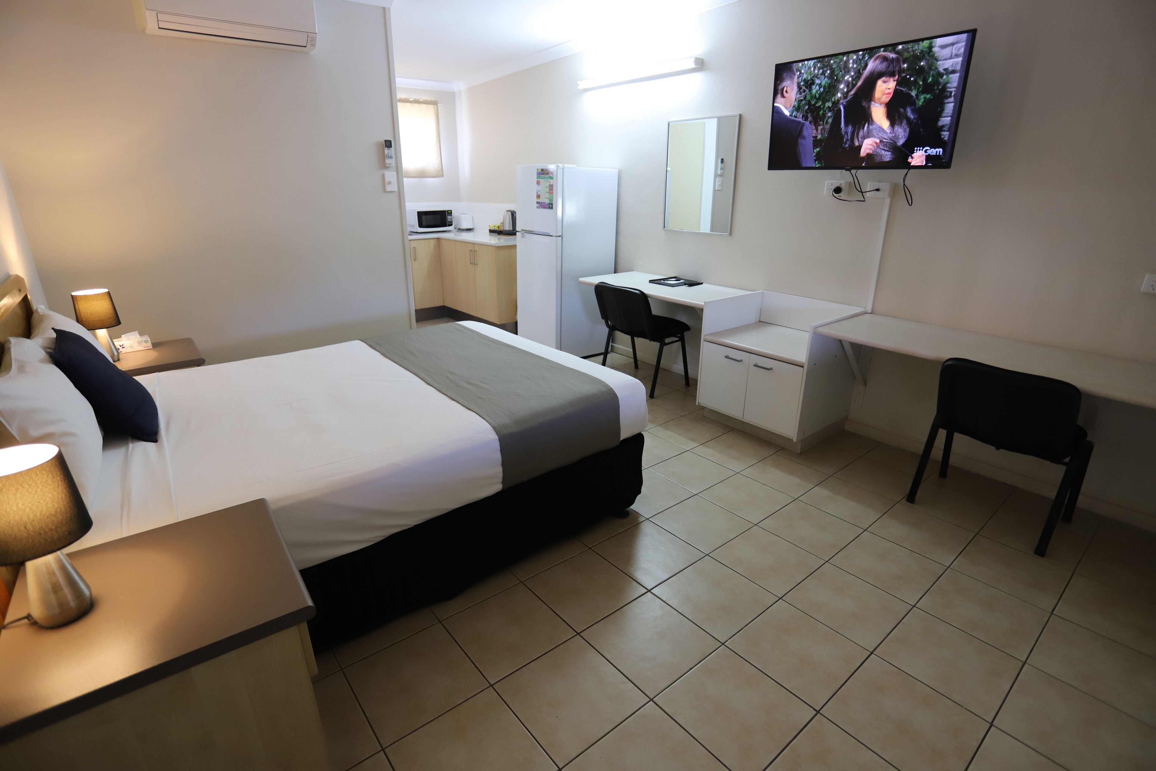 A hotel room with a bed, desk, chair, and TV.