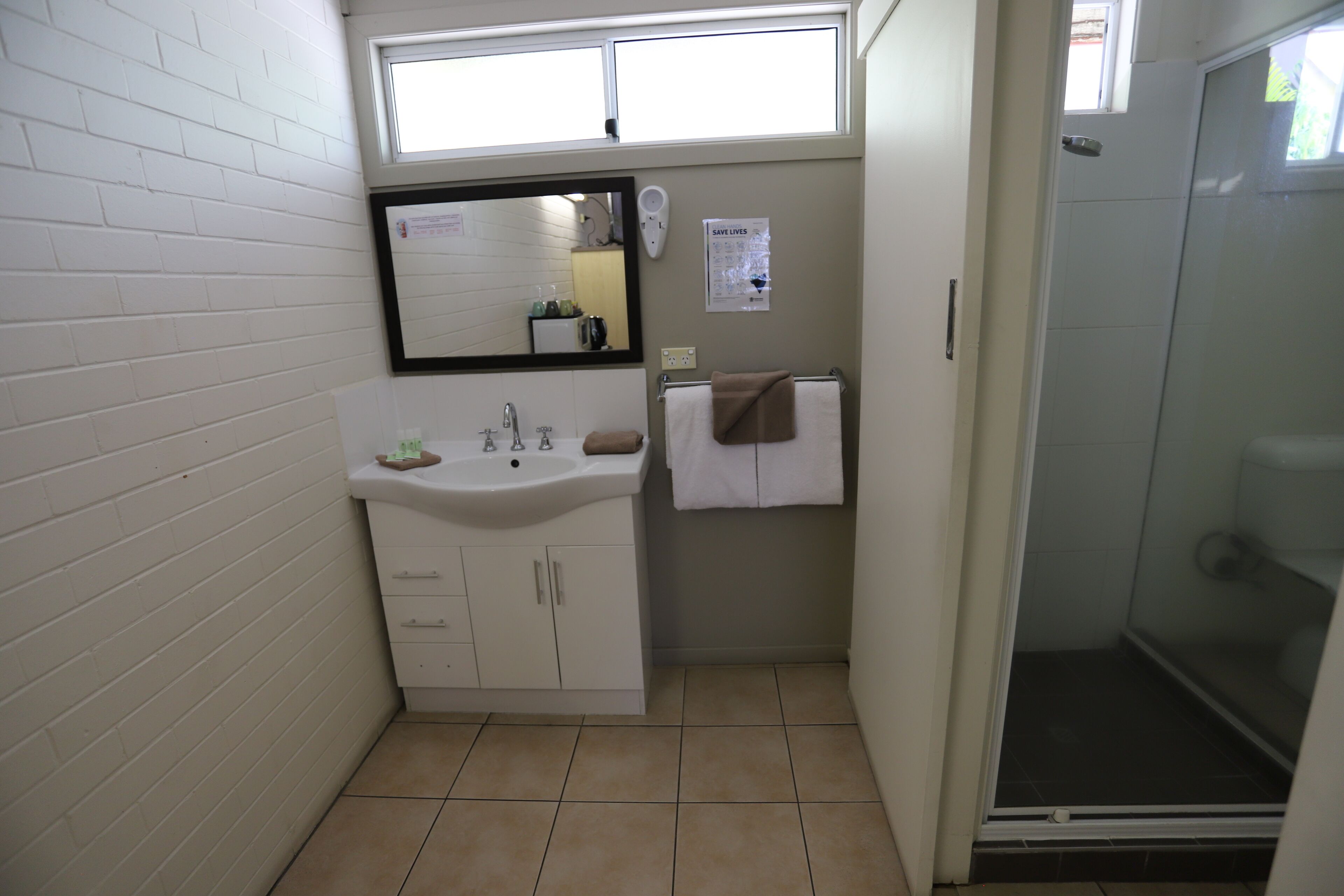 A bathroom with a white sink, mirror, and towel rack.