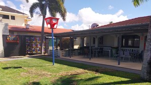 A motel with outdoor seating and a covered patio area. - Tropic Coast Motel (West Mackay)