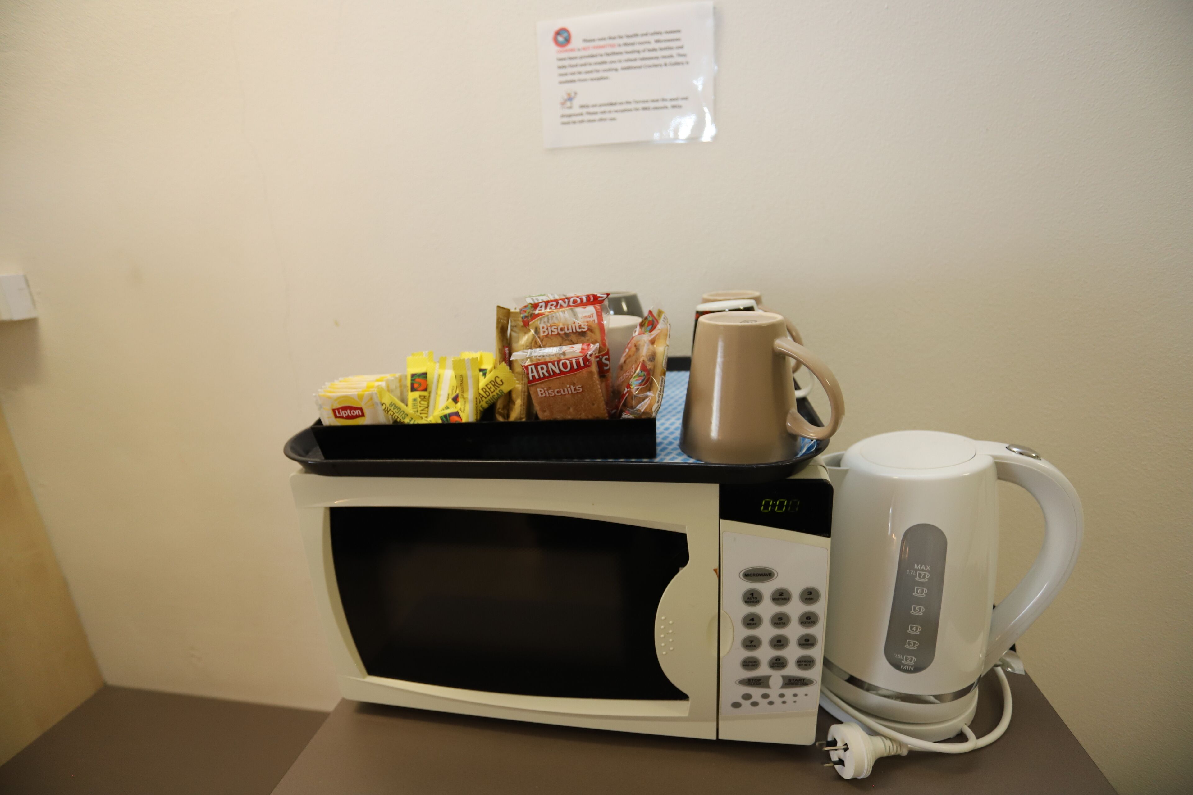Un four à micro-ondes avec une machine à café et des en-cas posés dessus.