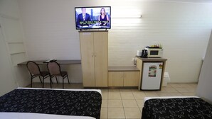 A hotel room with two beds, a television, a desk with chairs, a microwave, and a refrigerator. - Tropic Coast Motel (West Mackay)