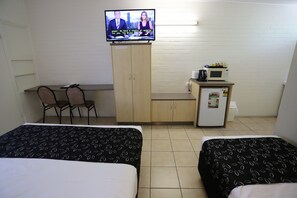 Une chambre d’hôtel avec deux lits, une télévision, un bureau avec des chaises, un four à micro-ondes et un réfrigérateur.