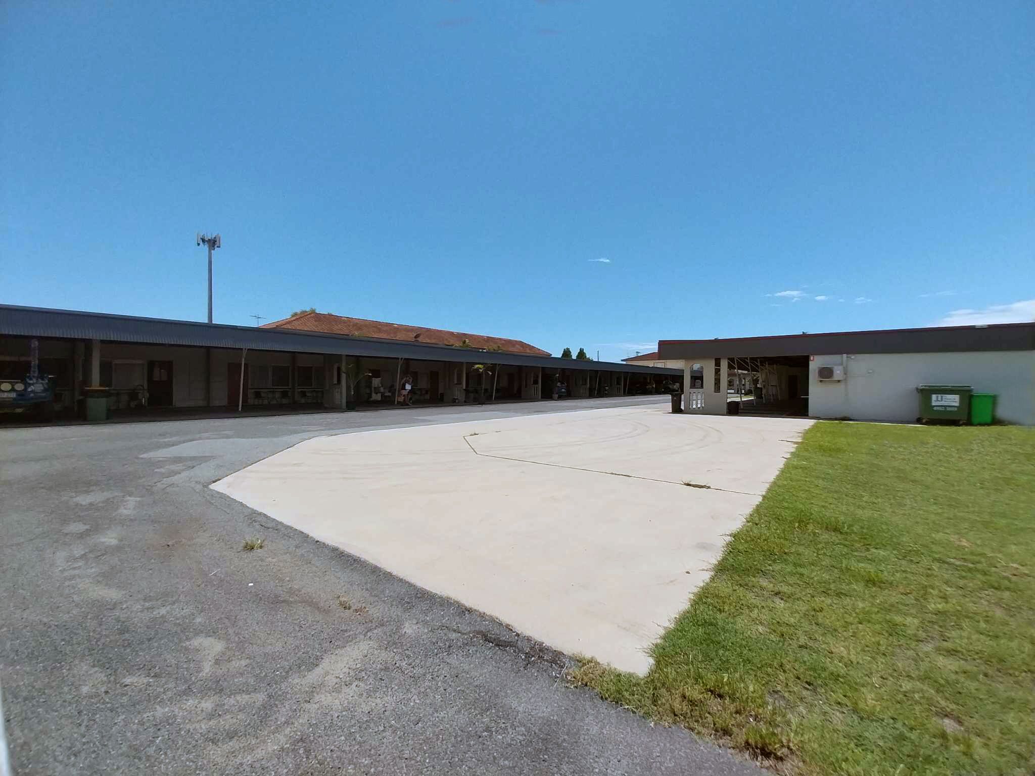 A large, open parking area with a building featuring multiple rooms and a covered outdoor area.