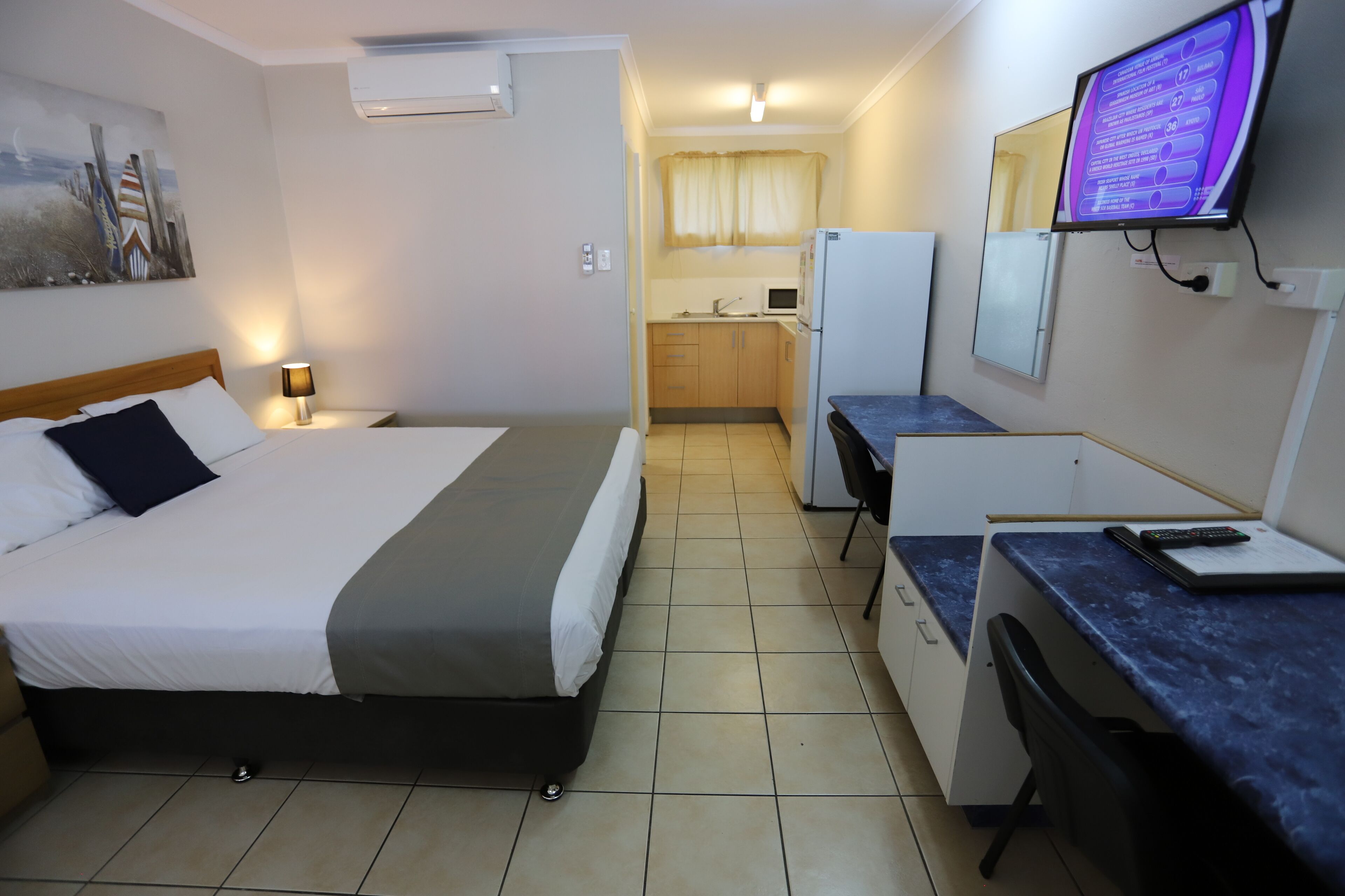 A hotel room with a bed, desk, chair, and a television.