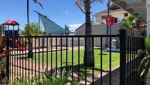 A fenced backyard with a playground, including a slide and a swing set. - Tropic Coast Motel (West Mackay)