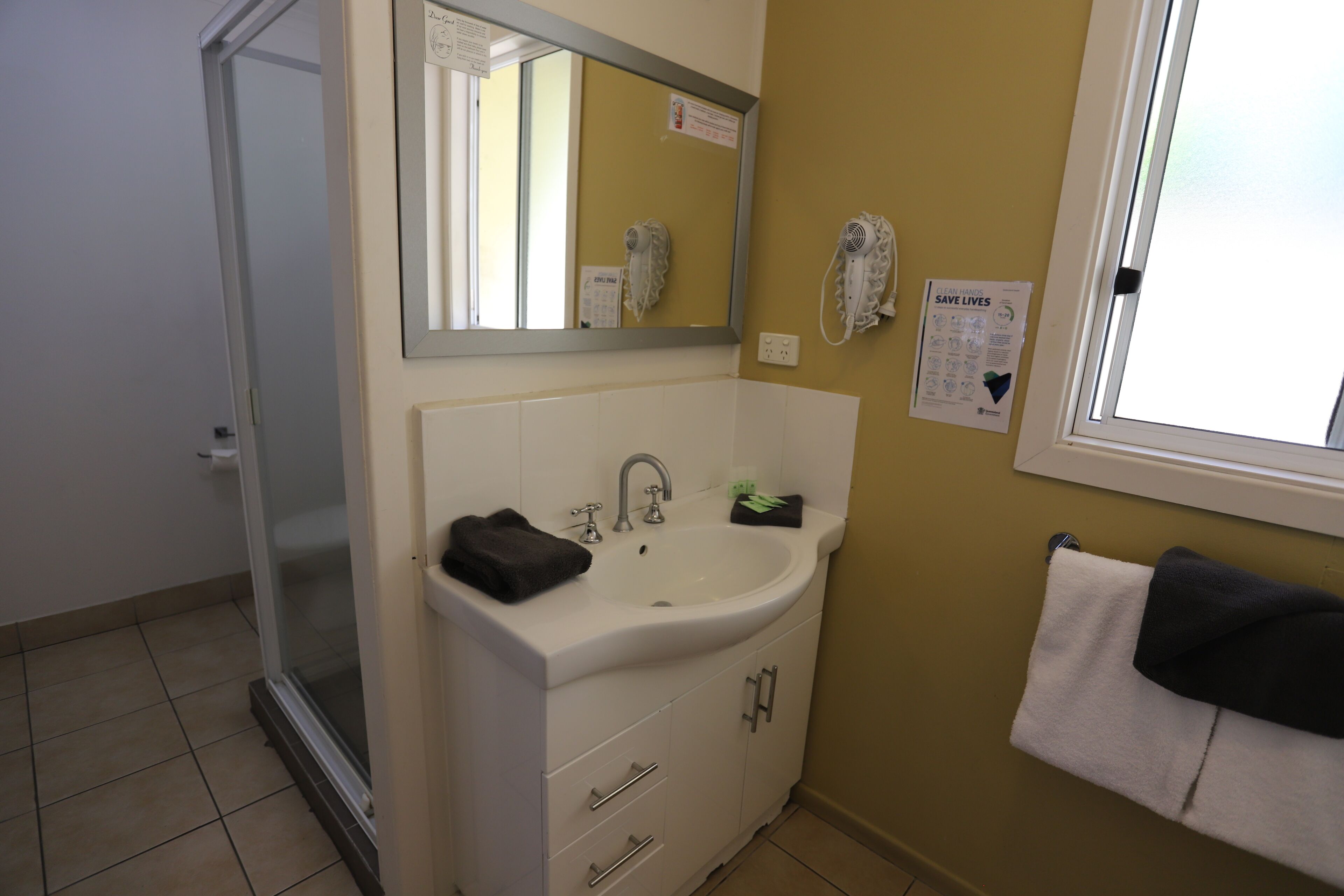 Une salle de bain avec un lavabo blanc, un miroir et un porte-serviettes.
