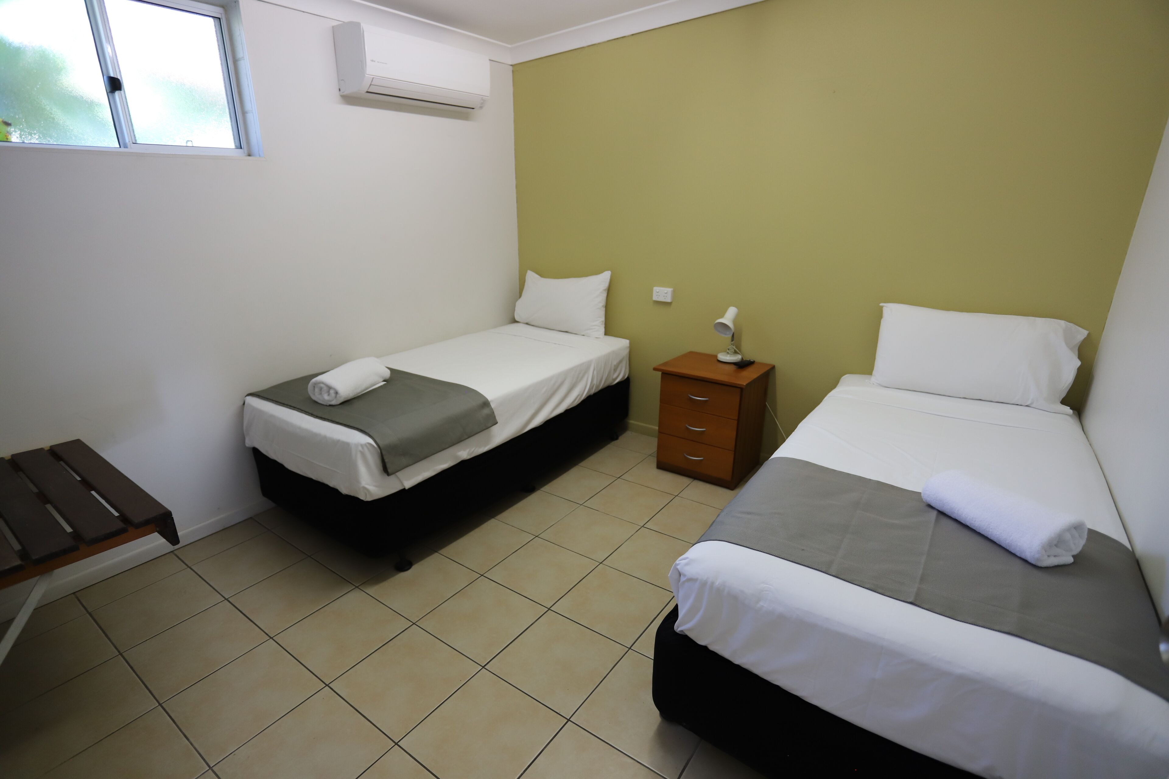 A room with two beds, a desk, and a window.