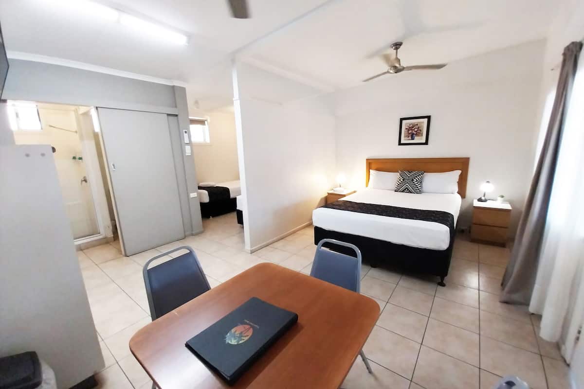 Une chambre d’hôtel équipée d’un lit, d’une table de chevet, d’une commode, d’un bureau, de chaises et d’un ventilateur de plafond.