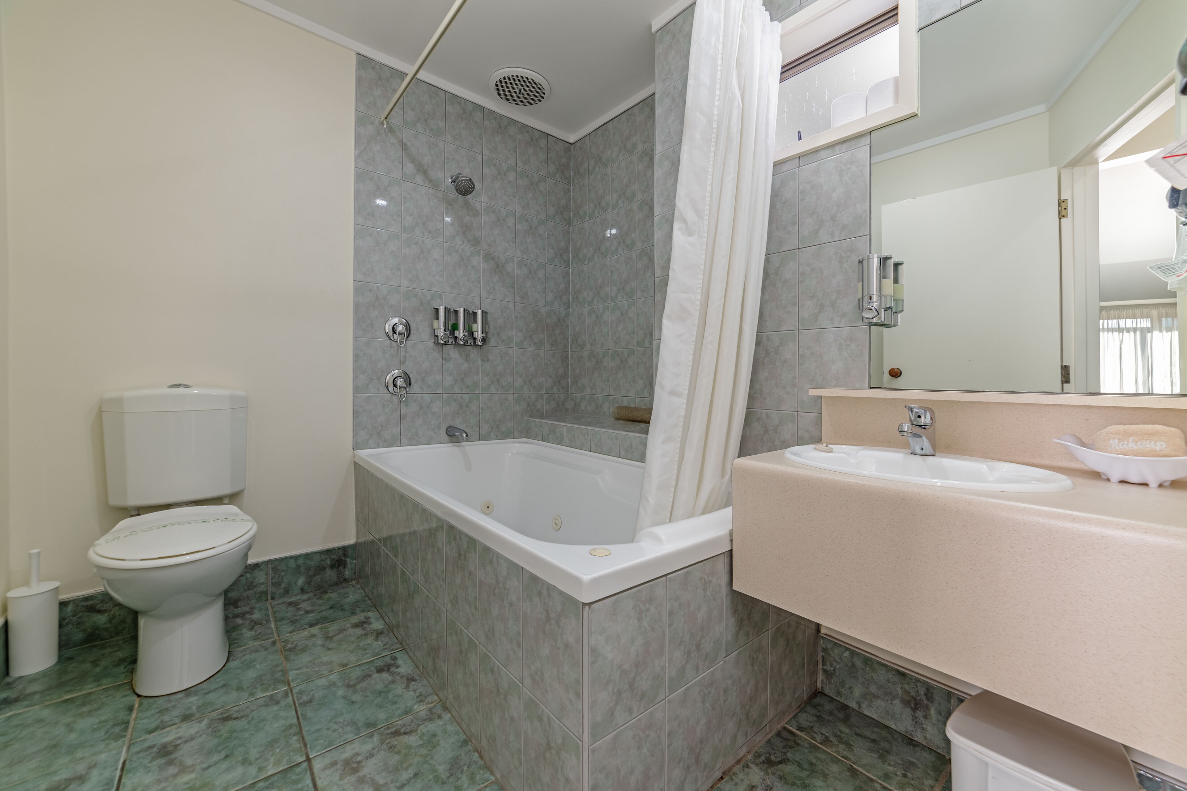 A bathroom with a bathtub, toilet, sink, and a mirror.