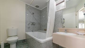 A bathroom with a bathtub, toilet, sink, and a mirror.