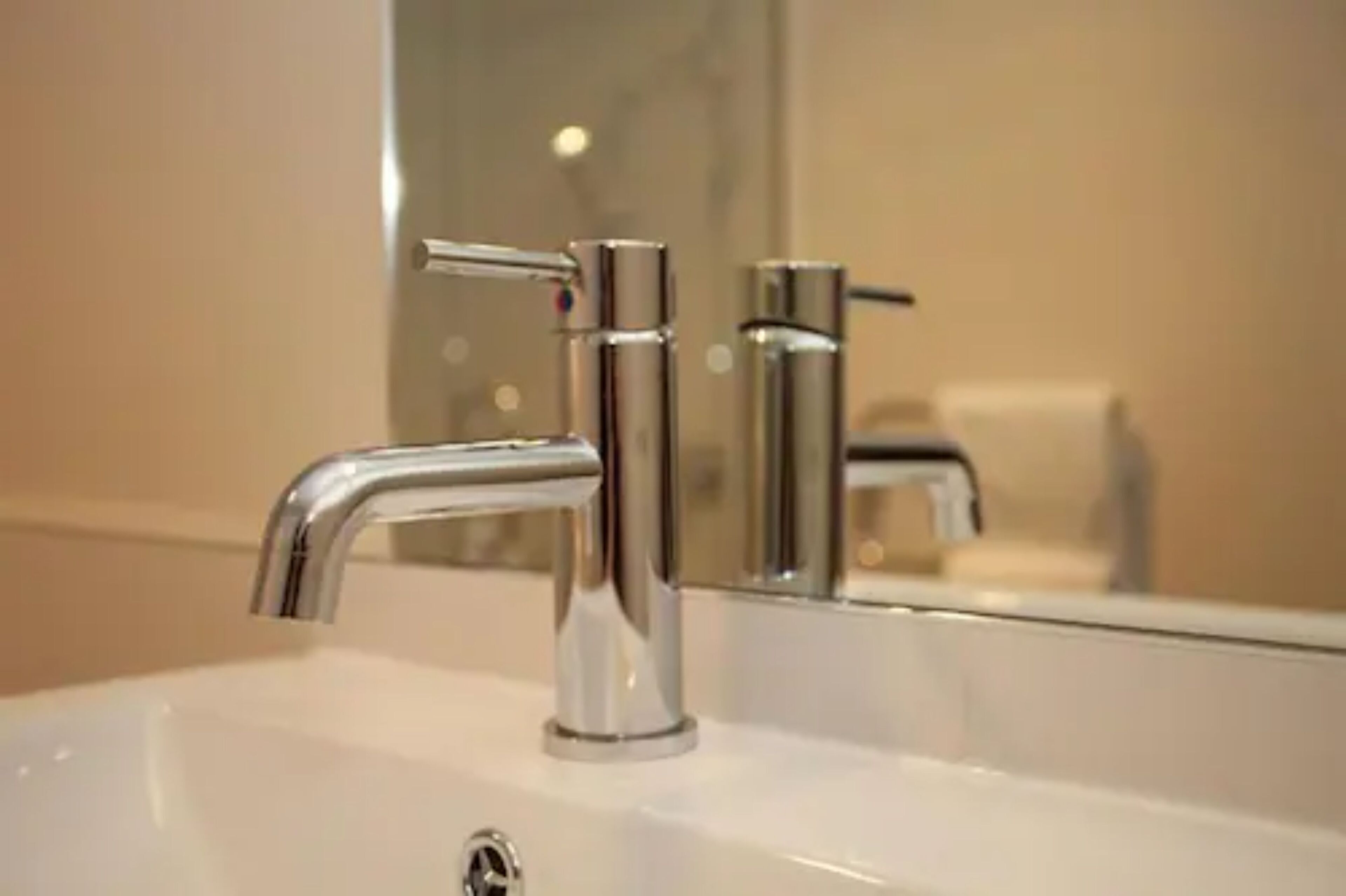 A modern bathroom with a chrome faucet and a mirror reflecting the sink.