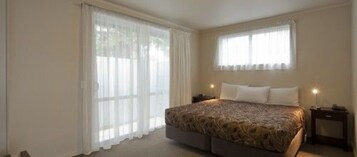 Un dormitorio con una cama grande, dos mesitas de noche y una ventana con cortinas.