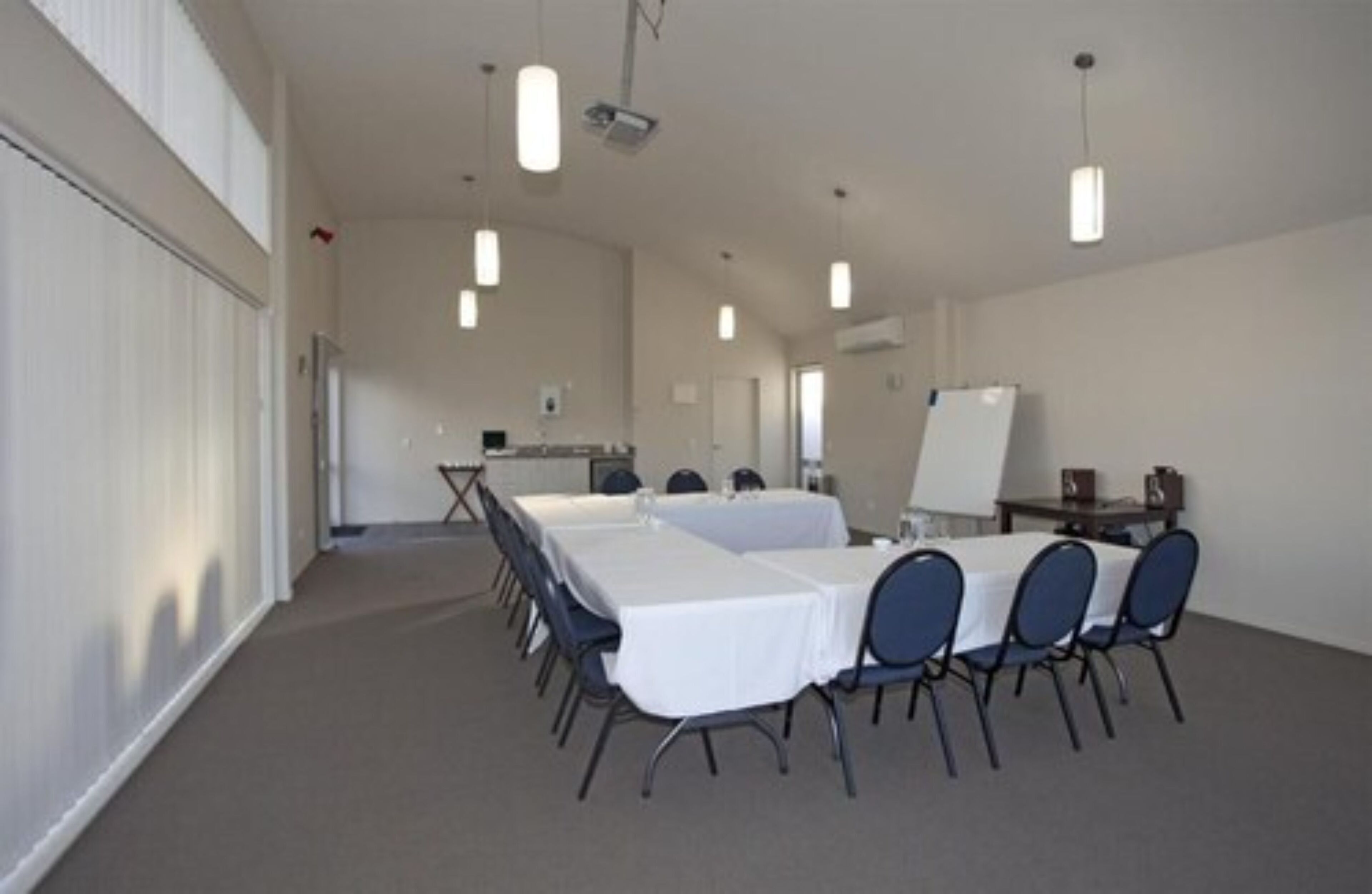 Een congreszaal met lange tafels, stoelen en een whiteboard.