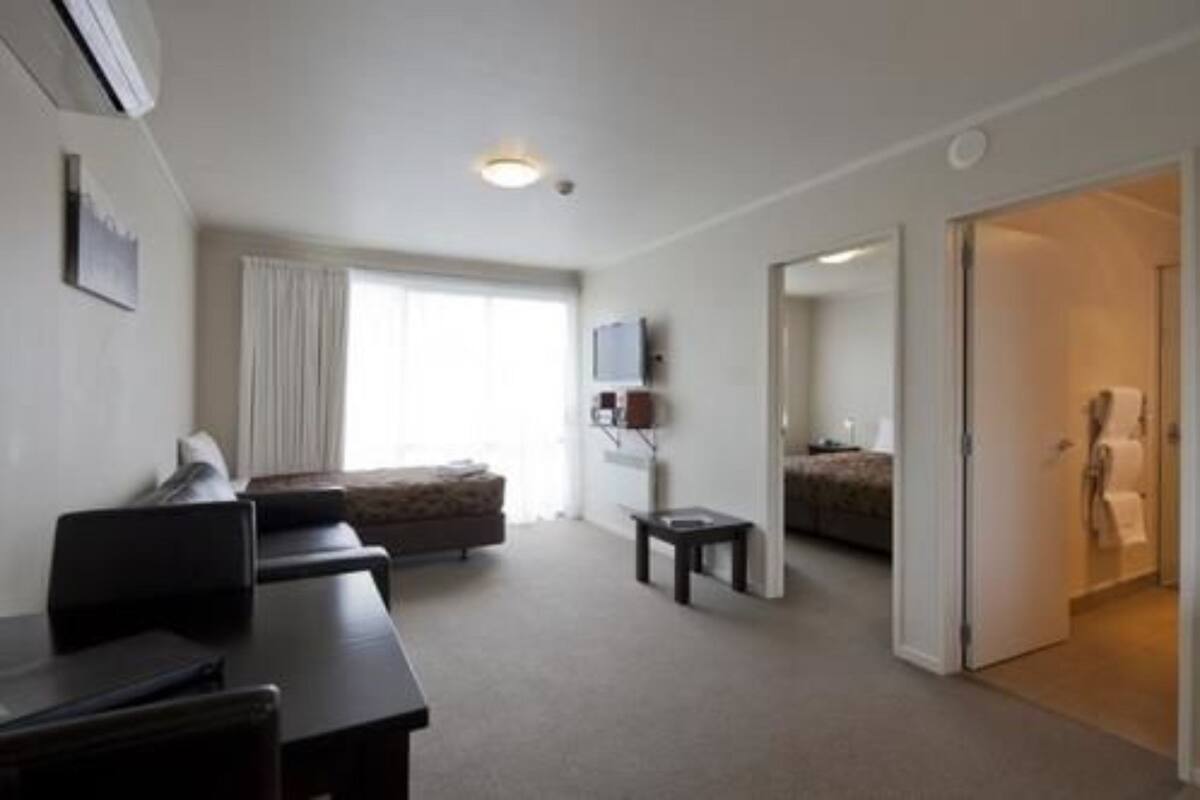 A hotel room with a bed, a desk, a chair, a television, and a window.