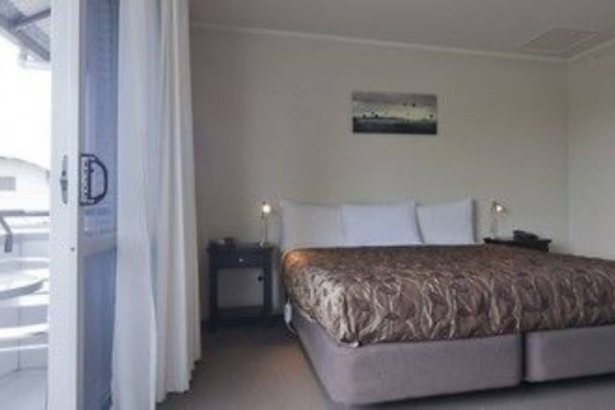 A hotel room with a bed, a desk, a chair, and a view of the outside.