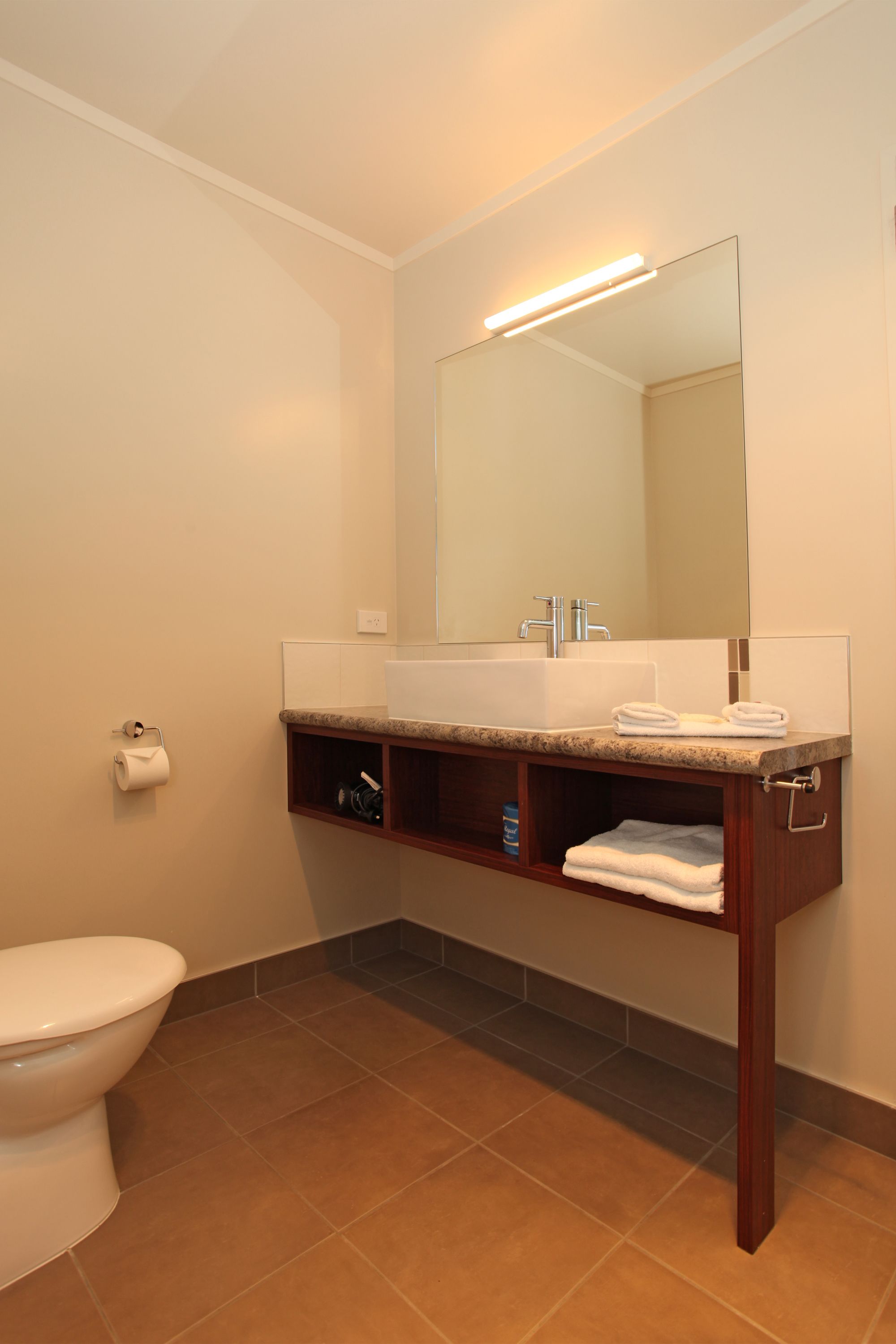 A bathroom with a white toilet, a sink with a mirror above it, and a towel rack.