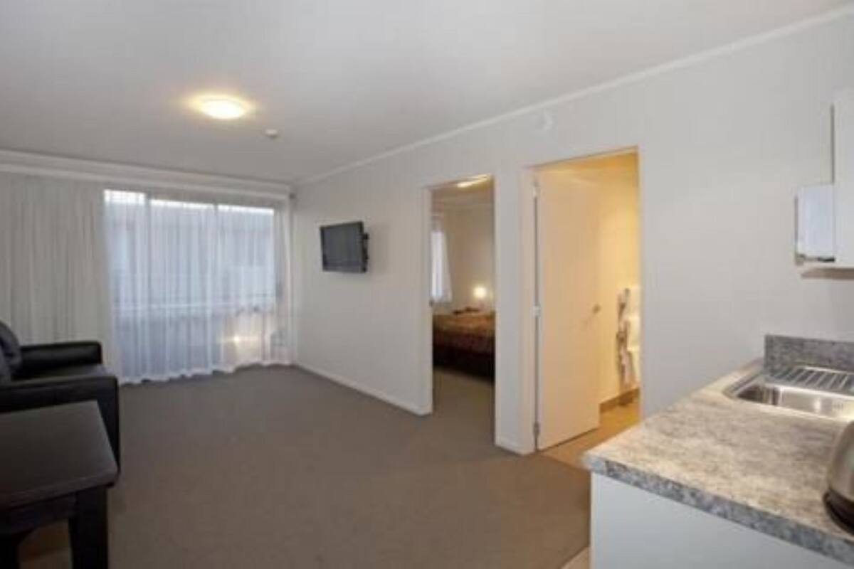 A hotel room with a kitchenette, a bed, a TV, and a bathroom.