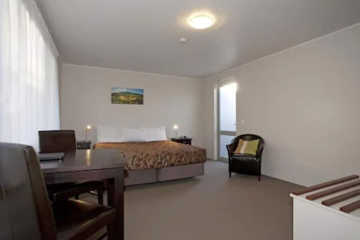 A bedroom with a bed, a desk, and a chair.