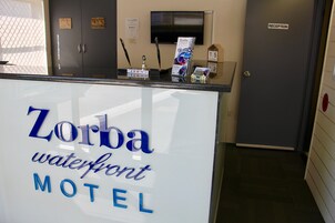 Eine Rezeption im Zorba Waterfront Motel mit einem Schild, einem Fernseher und einem Kleiderständer.