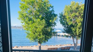 Un balcón con vista a un lago, una zona verde y un banco de madera.