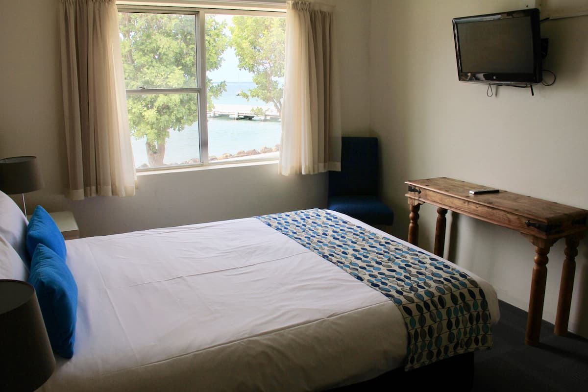 A hotel room with a bed, a desk, a chair, a television, and a window with curtains.