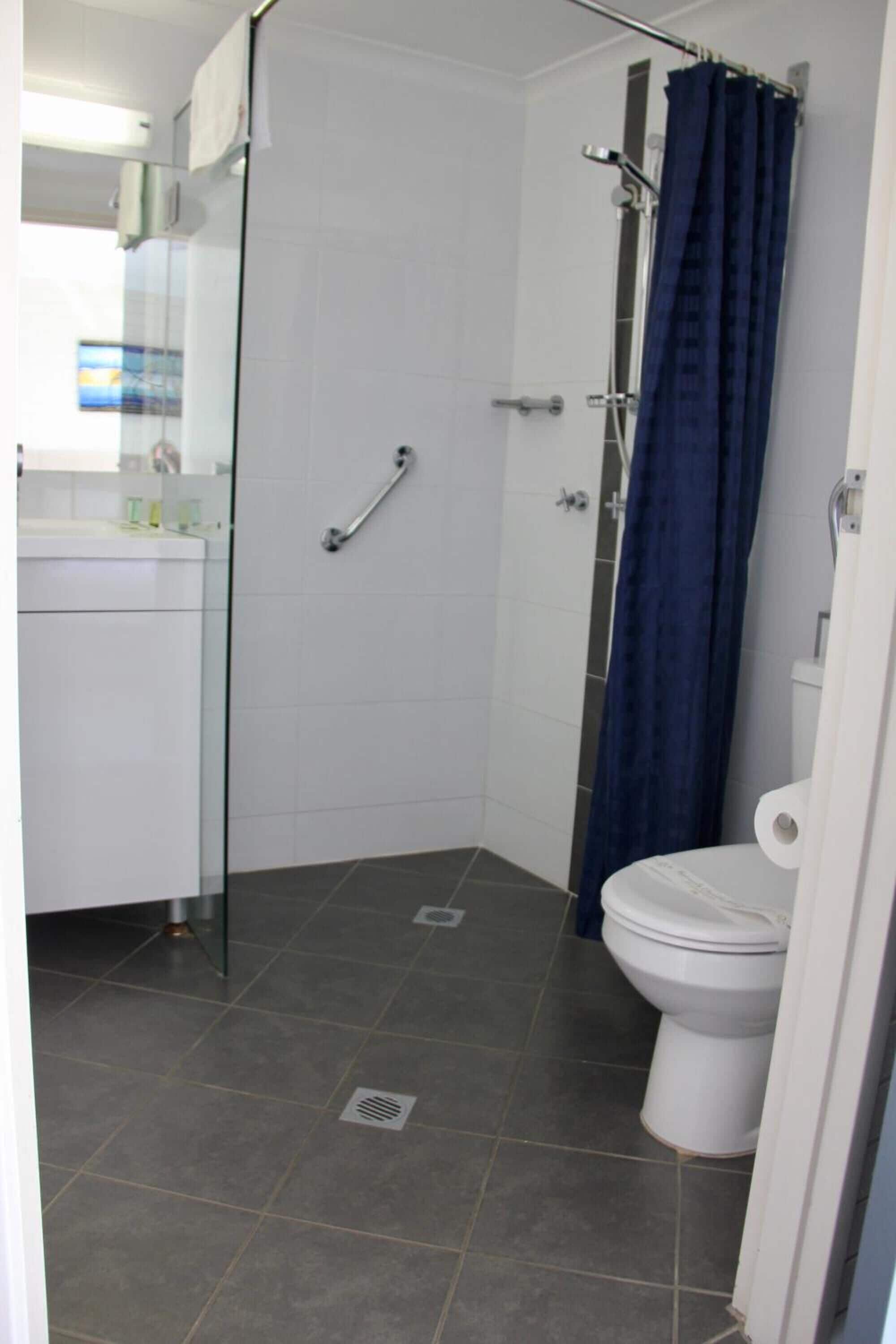 A bathroom with a glass shower enclosure, a white toilet, and a glass door leading to a shower area.