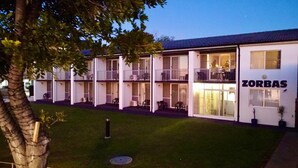 Un hotel de varios pisos con balcones y un letrero que dice "ZORBAS".