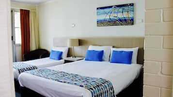 A hotel room with two beds, a desk, a chair, a lamp, and a painting on the wall.