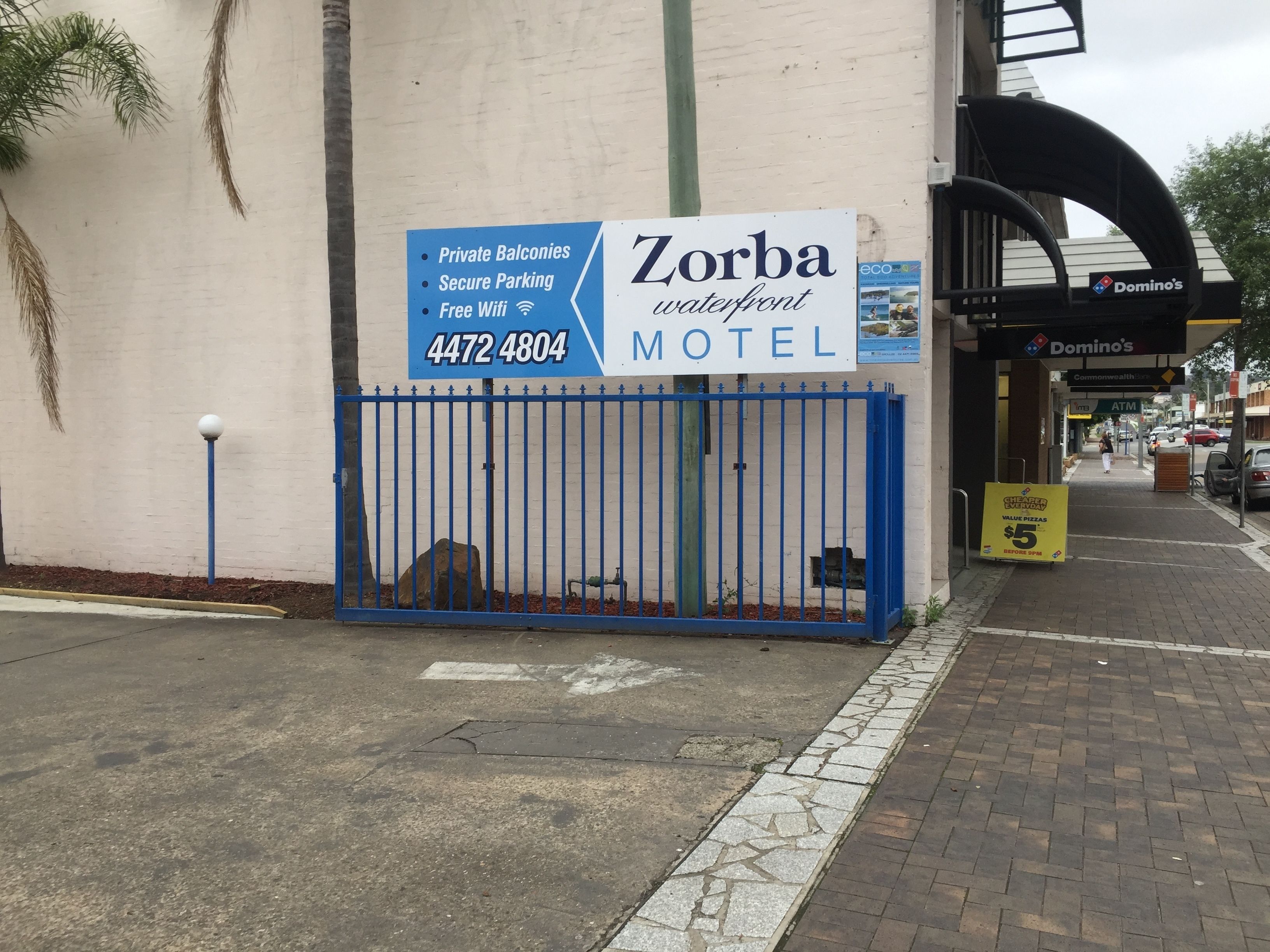 A Zorba waterfront motel sign with amenities like private balconies, secure parking, and free wifi.