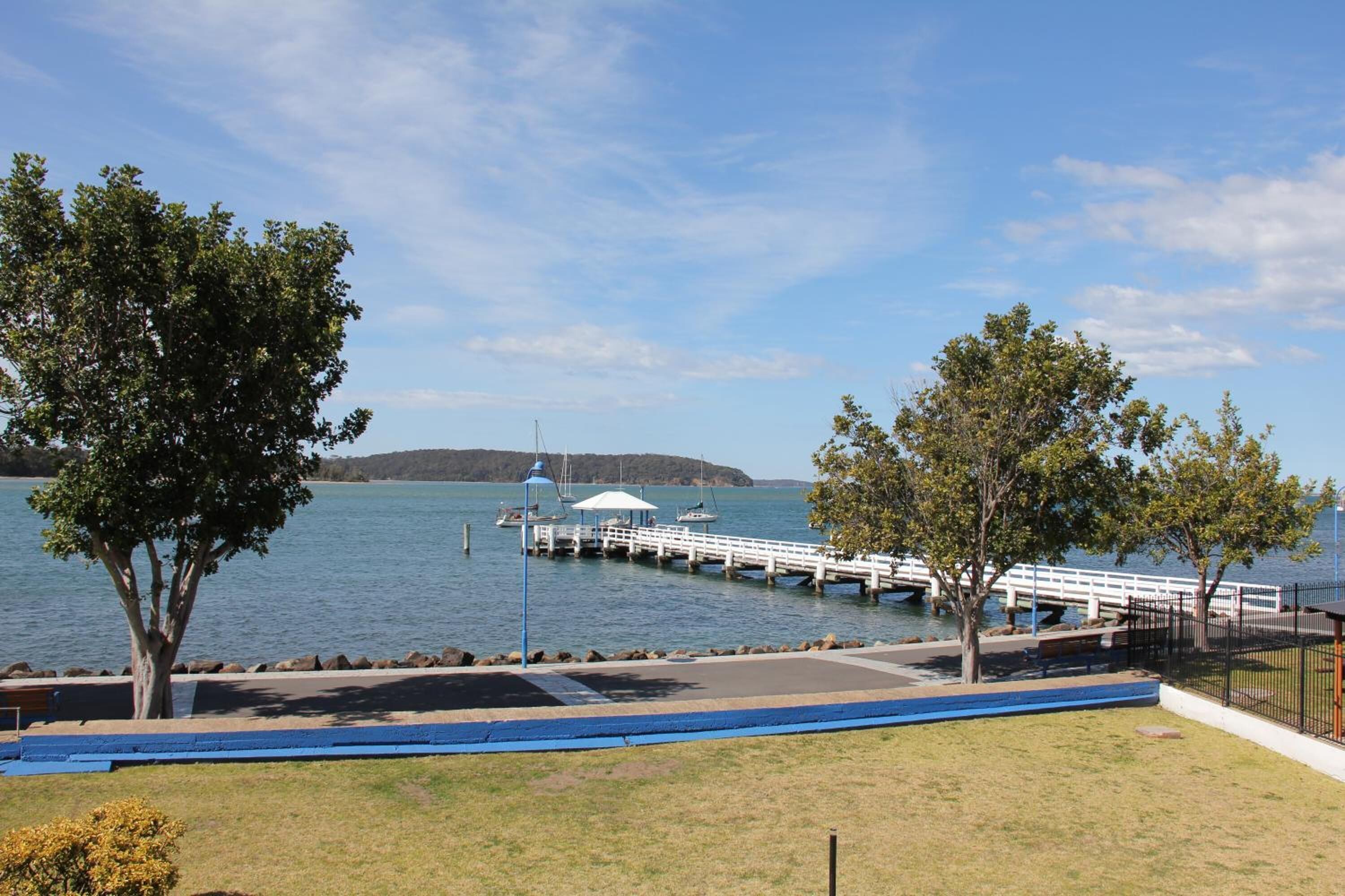 A lakeside park with a dock, benches, and a gazebo.