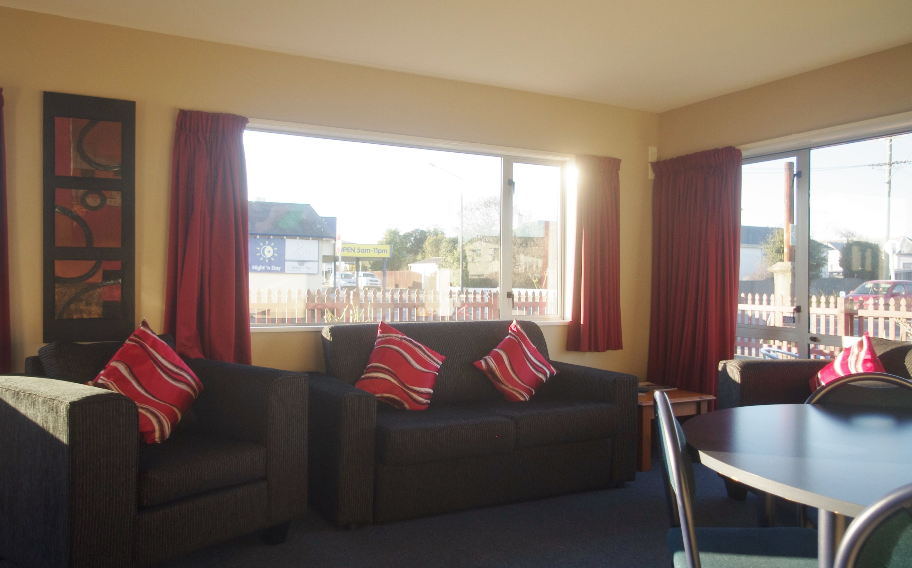A room with two sofas, a dining table, and a large window with curtains.