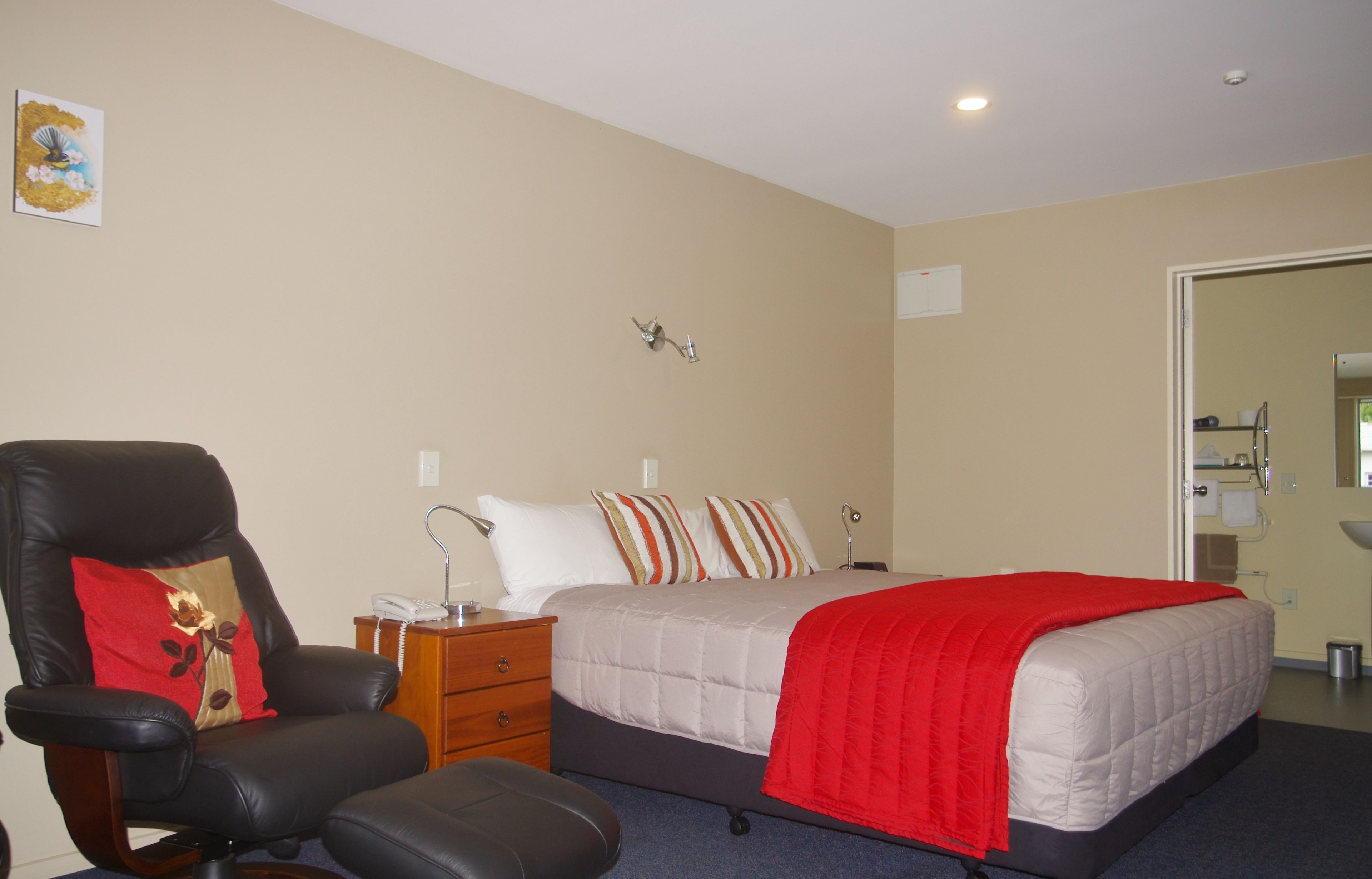 Una habitación de hotel con una cama, una silla, un escritorio y un espejo.