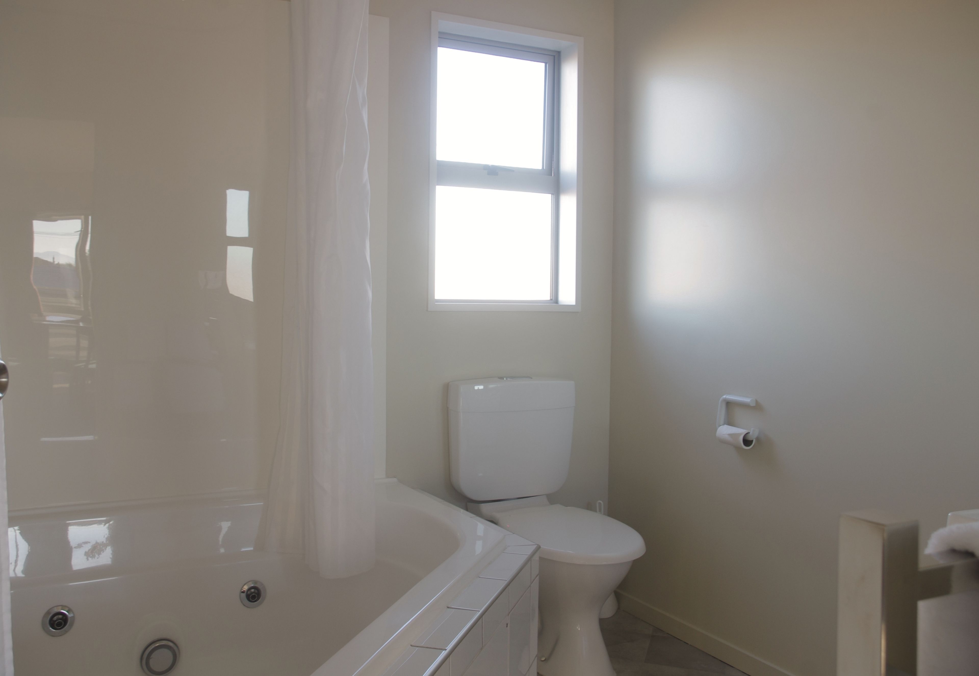 Et badeværelse med badekar, toilet og et vindue.