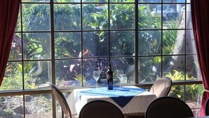 A table set for two with a view of a garden through a large window. - Riverview Motor INN Taree (Taree)